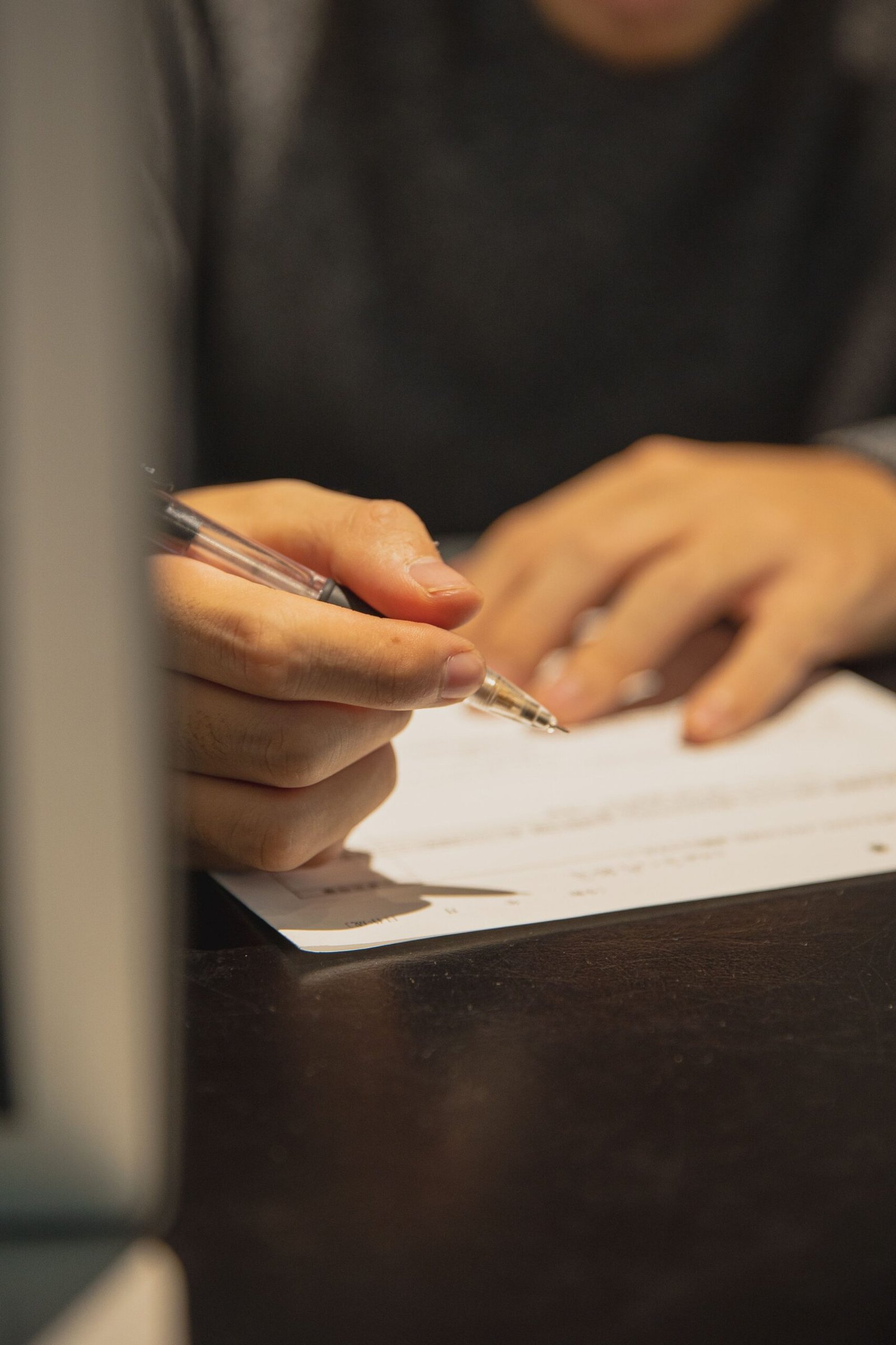 يد رجل تكتب بقلم على ورقة مستندات